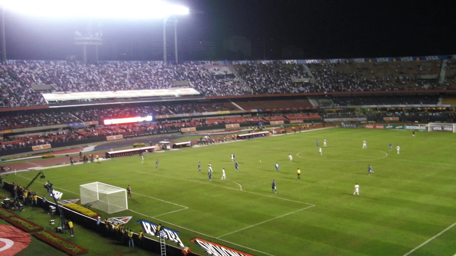 Jogadores em campo durante partida de futebol do Avaí em estádio com arquibancadas cheias
