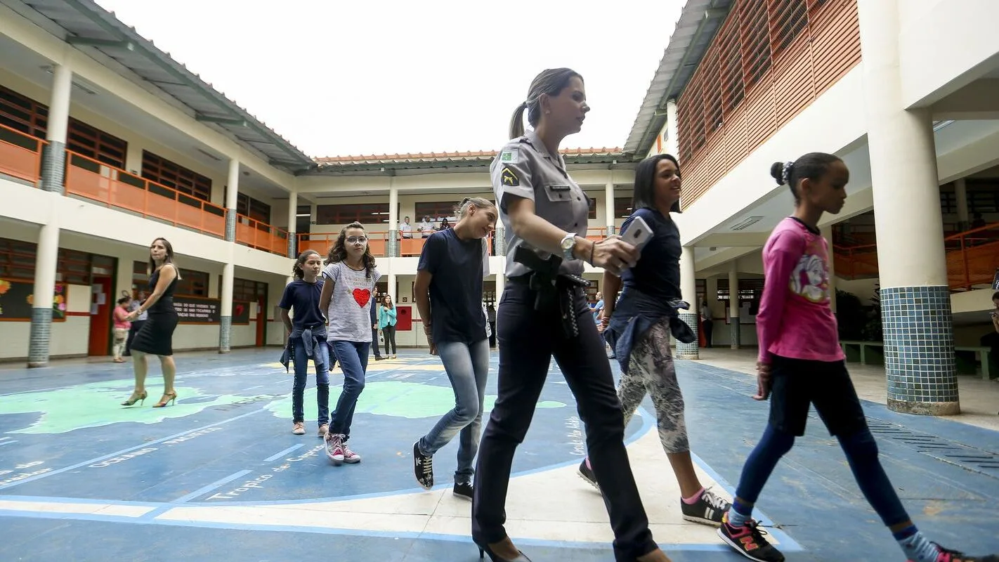 Pátio de escola estadual em Minas Gerais, com estudantes e funcionária