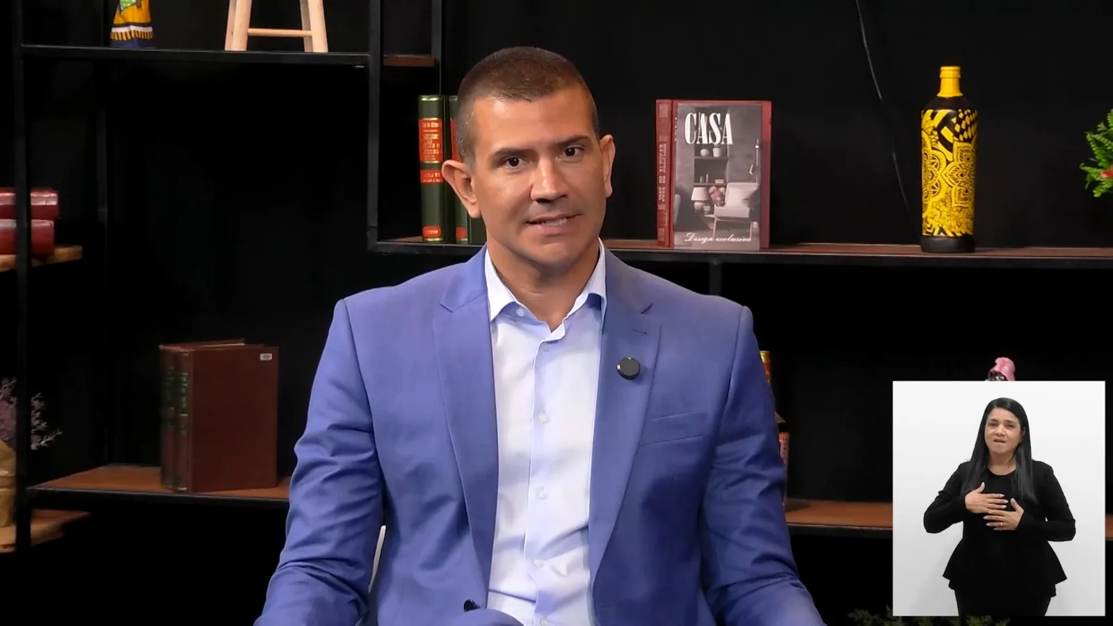 Douglas Ruas sorri durante entrevista, vestindo terno azul