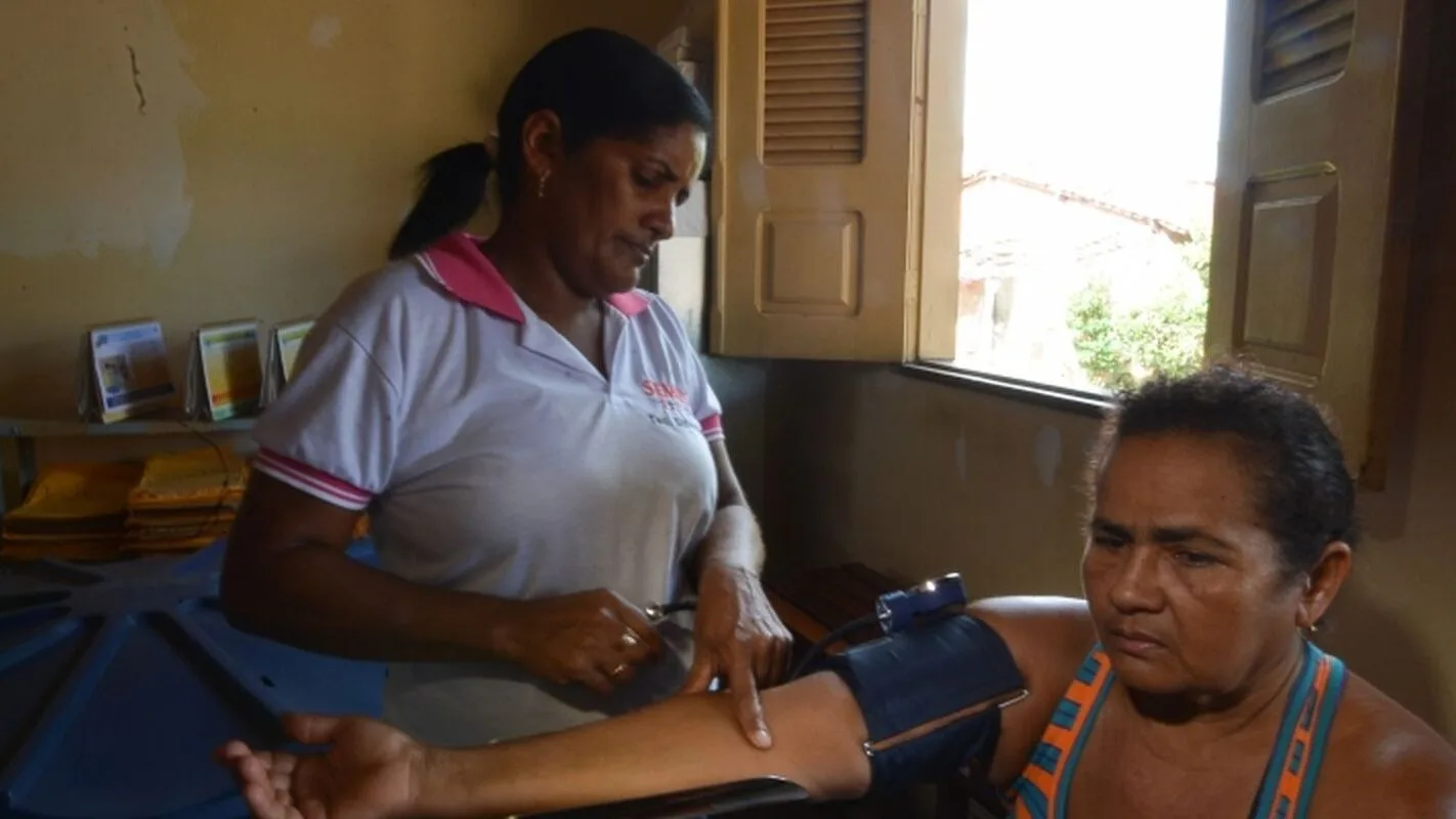 Profissional de saúde mede a pressão arterial de uma paciente em consulta