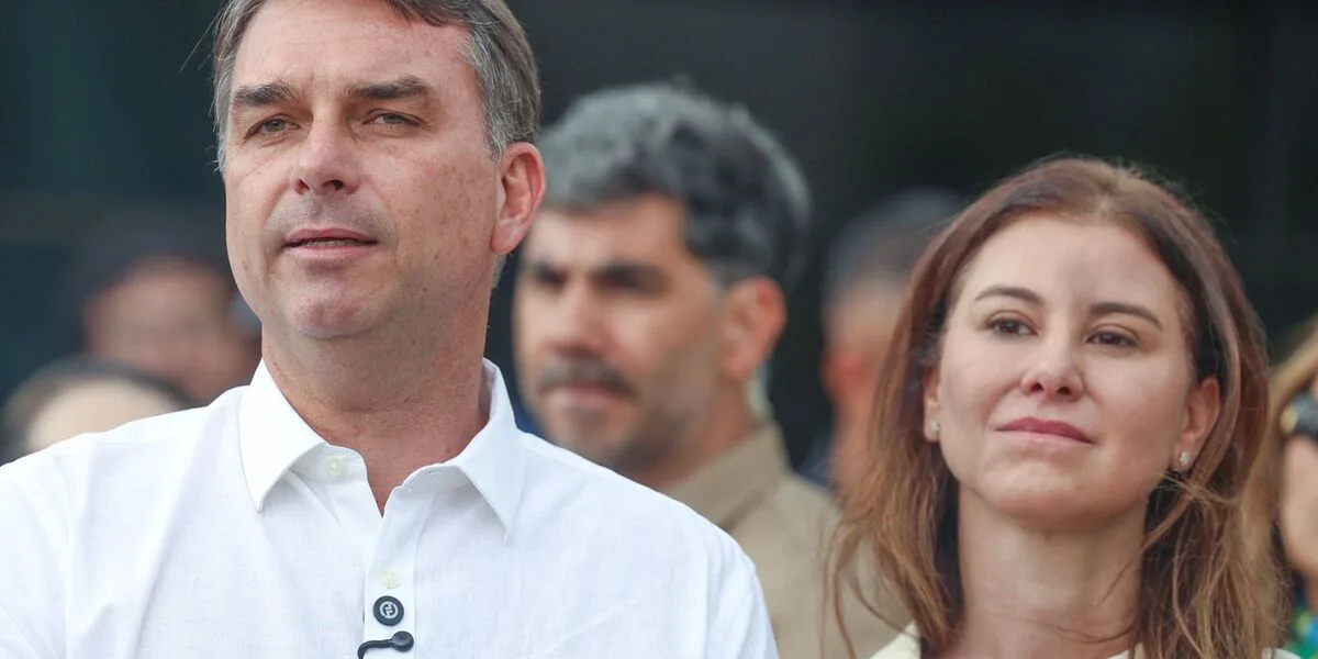 Flávio Bolsonaro em meio a apoiadores, ao lado de uma mulher, durante ato de campanha