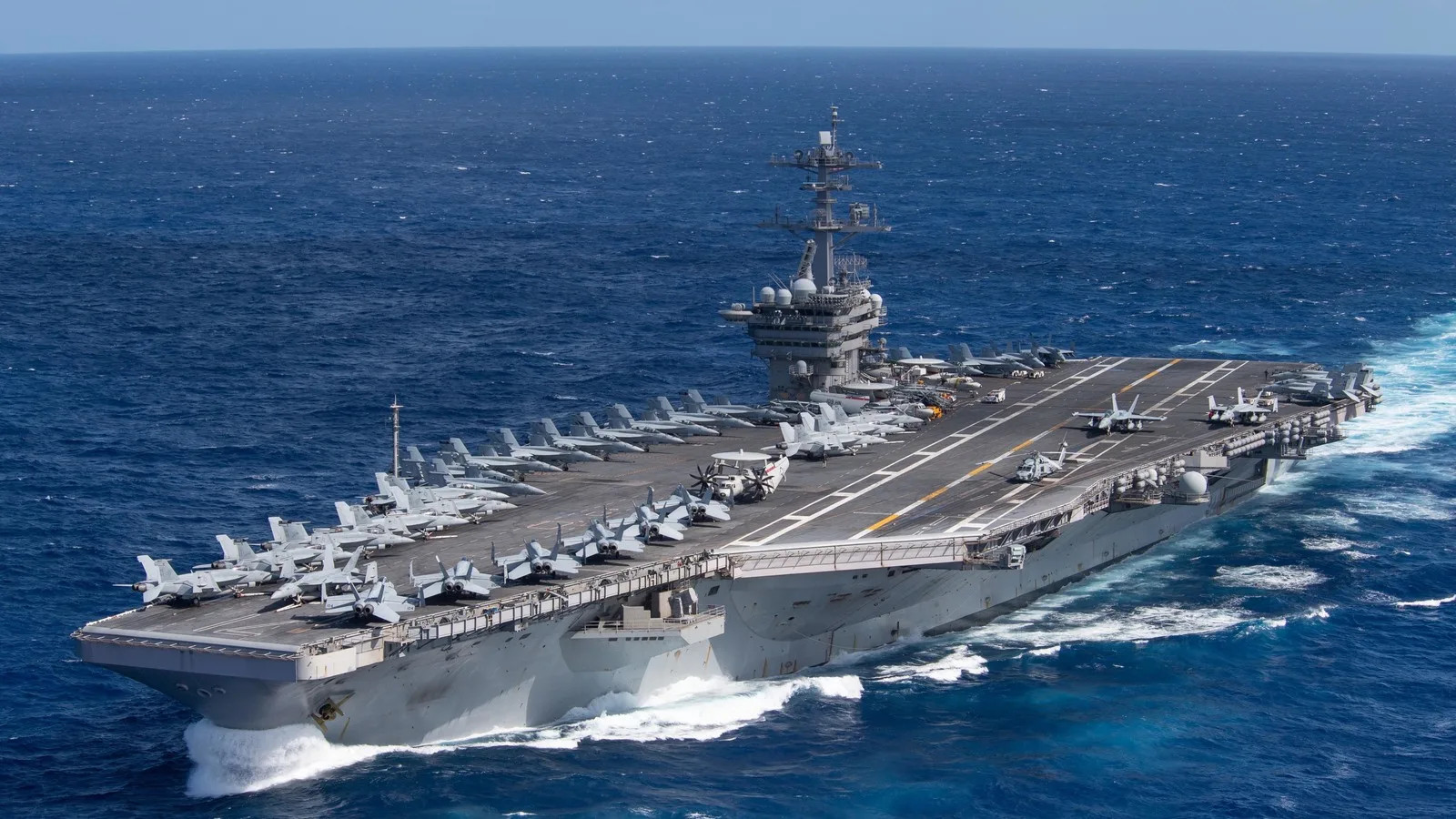 Porta-aviões USS Theodore Roosevelt navegando em alto-mar, com caças posicionados no convés
