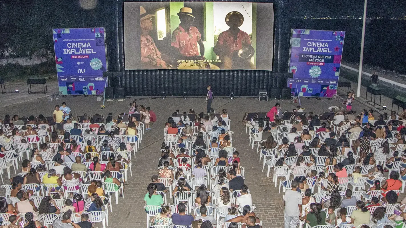 Plateia assiste a sessão de cinema ao ar livre à noite