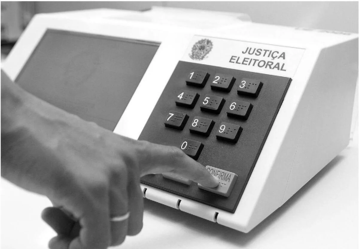 Mão de eleitor digita número de candidato em urna eletrônica da Justiça Eleitoral