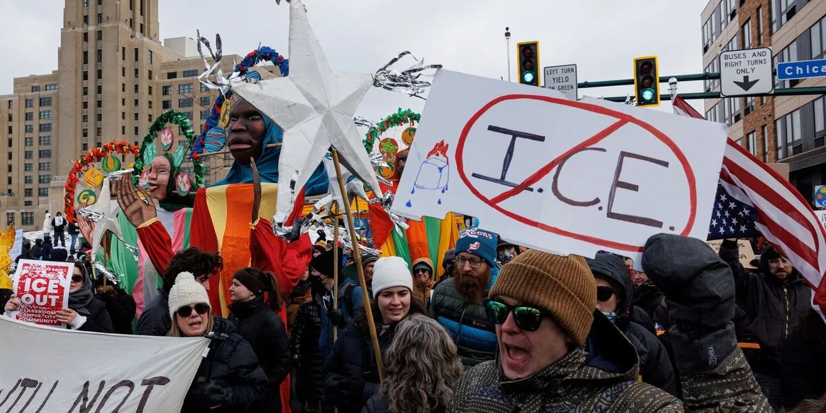 Manifestantes protestam contra o ICE em rua dos Estados Unidos, com cartaz com a sigla riscada