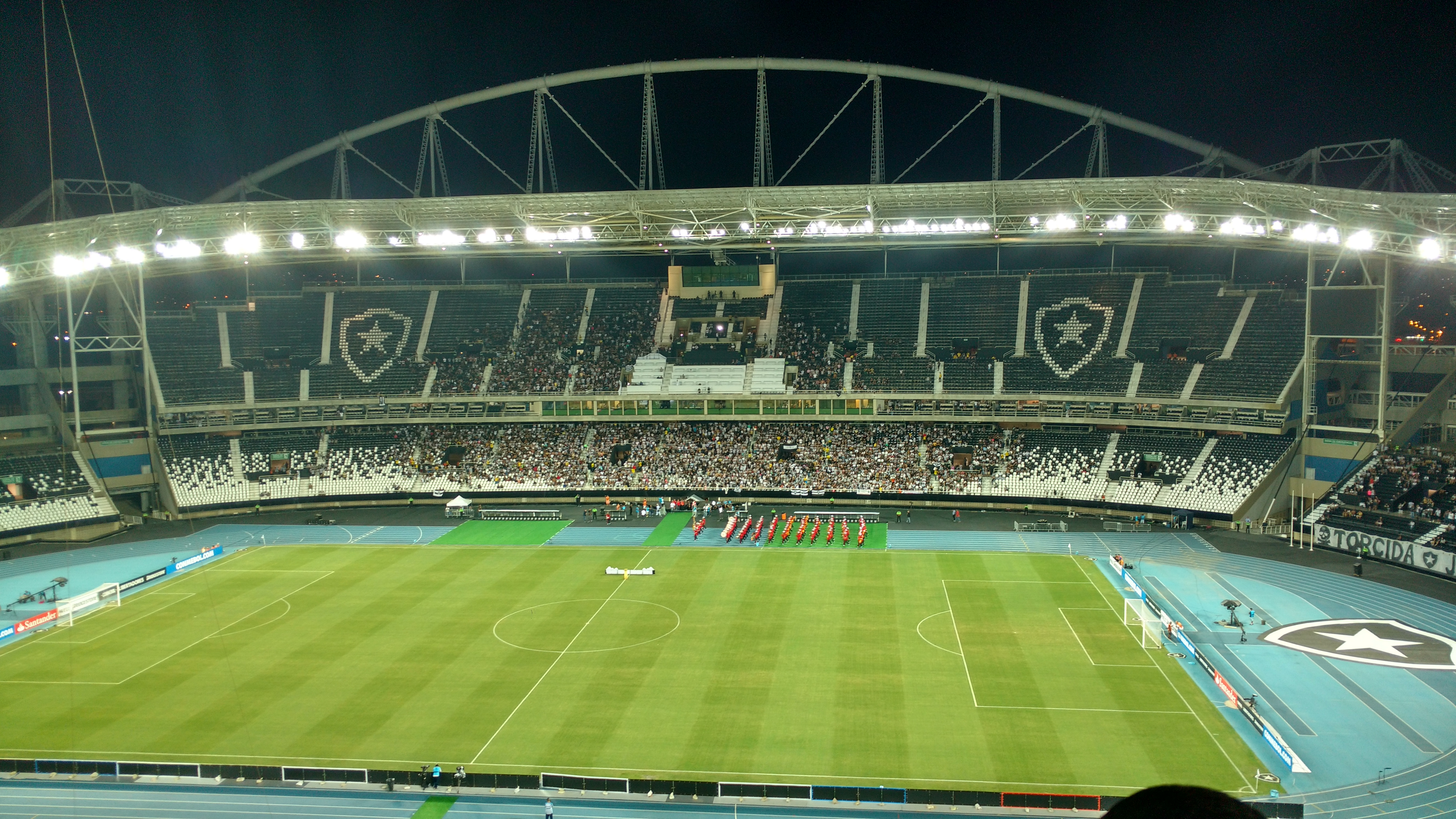Estádio Nilton Santos à noite, em jogo do Botafogo, com torcida nas arquibancadas